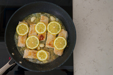 Hake fillets sizzle in a garlic butter sauce with fresh lemon for a zesty flavor.