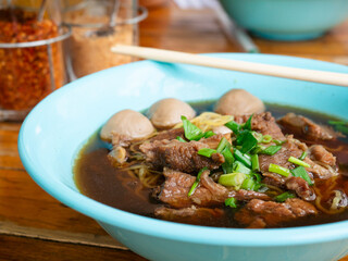Braised beef noodle soup set on wooden table.