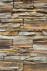 Stone wall made from stacked flat stones in various earthy tones and textures.