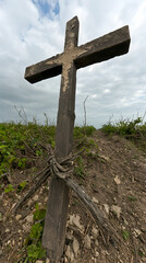Weathered wooden cross on a hill, cloudy sky, remembrance, historical site, stock photo