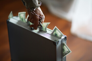 Handcuffed Person Grabbing Money-Filled Briefcase - Financial Crime Concept