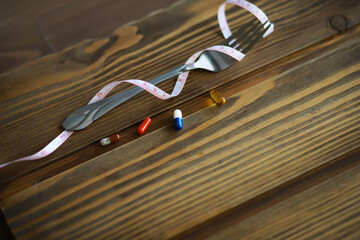 Diet Concept with Measurement Tape and Various Pills on Wooden Surface