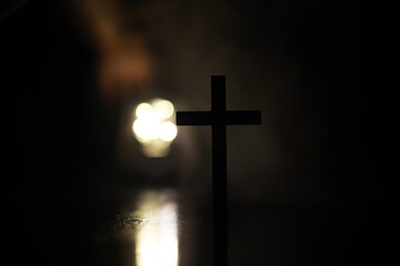 Silhouette of Wooden Cross Backlit by Blurred Light in Dark Setting