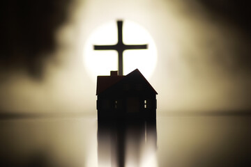 Silhouette of House and Cross Against Glowing Background in Dark Atmospheric Setting