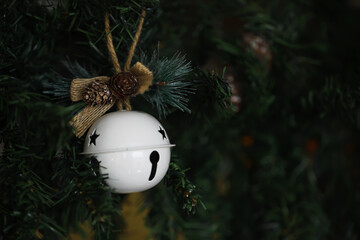White Christmas Bell Ornament on Pine Tree with Greenery and Pinecone Decorations