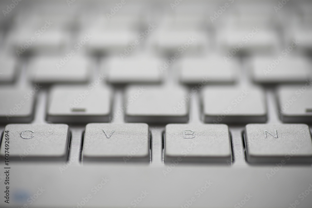 Poster close-up of white keyboard with focus on cvbn keys in modern office setting