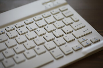 Close-up of Modern White Wireless Keyboard on Wooden Desk