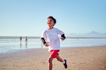 Carefree boy enjoying summer vacation running on the beach