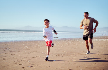Father and son running on the beach, enjoying a healthy lifestyle together