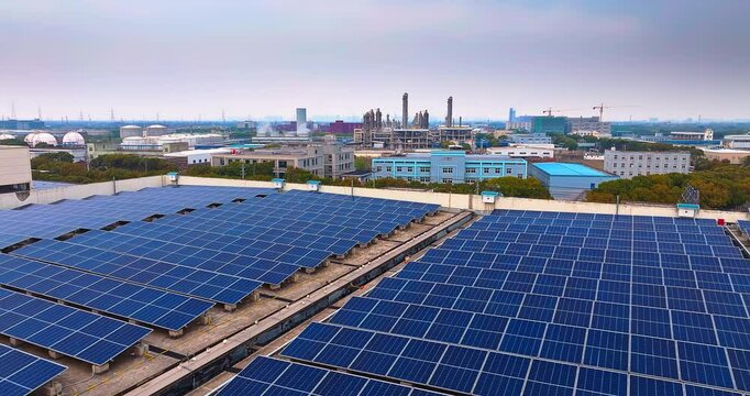 Aerial view of solar panels installed on industrial rooftops generating renewable energy with a chemical plant.