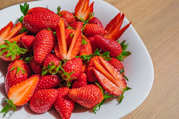 Delicious fresh red strawberries in a white bowl on a wooden background
