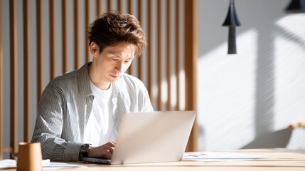 Financial planning retirement spreadsheet Focused man working on a laptop in a well-lit, modern workspace.