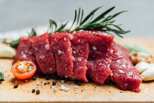 Close-up of raw Steak with fresh tomatoes, garlic and rosemary on a wooden chopping board