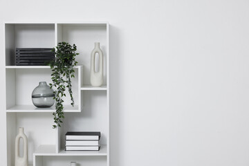 Shelving unit with decor near white wall indoors, space for text