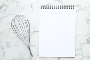 Blank recipe book and whisk on white marble table, top view. Mockup for design