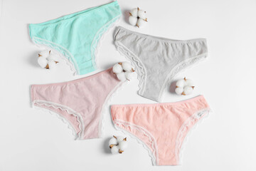Women's underwear. Beautiful panties and cotton flowers on white background, flat lay