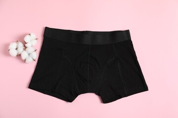 Comfortable black men's underwear and cotton flowers on pink background, flat lay
