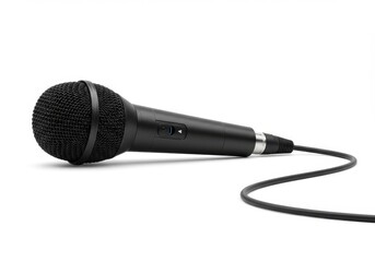 A black microphone with a cable laying on a white surface in a studio setting for recording audio