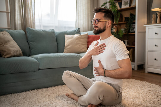 Young man practicing deep breathing exercise at home