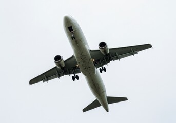 Airplane approaching for landing with landing gear down against a pale overcast sky background