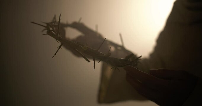 Jesus Christ holding a crown of thorns in ambient, glowing light as visual representation of good Friday and the crucifixion of Jesus on the cross. Perfect for Easter visual or gospel symbolism.