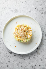 A creamy pasta dish layered with chopped vegetables and topped with a golden, crunchy breadcrumb crust, elegantly presented on a simple white plate.
