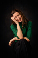 Carefree brown haired woman laughing against a dark background
