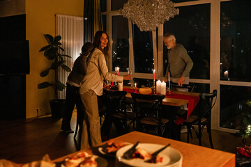 A European woman in her 30s, an elderly grandfather, and a grandmother in her 60s are standing at a...
