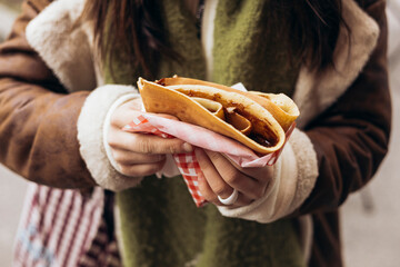 Woman holds a crepes pancake in a disposable package, takeaway fast food.