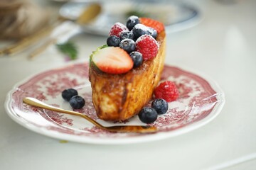 Delicious French Toast topped with fresh Strawberries Raspberries and Blueberries served on a vintage plate