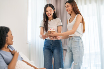 Multicultural group of women friends happy surprising friend with birthday cake at joyful party, celebration of friendship and happiness, happy birthday, candles, smiles, gift and fun at home