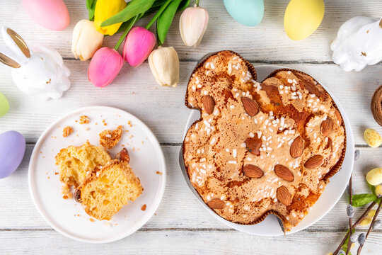 Italian Easter Colomba Cake, Colomba di Pasqua, sweet sugared dove-shaped sponge cake with glazed nuts and fruits, festive fruit- stuffed bread on white Easter holiday decorated table copy space