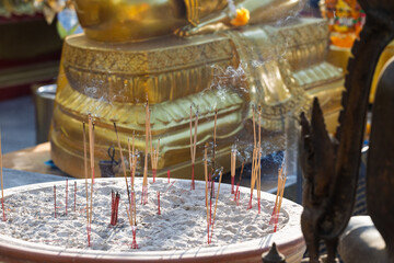 Burning aroma sticks with thick smoke in a circle incense bowl. Smoking incense sticks outdoors in wat at Thailand. Offering for the deities in buddhist temple at asia