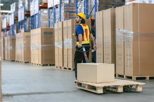 caucasian worker in a warehouse using hand pallet truck jack stacker to moving pallets good cargo,