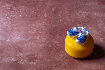 Obraz premium Traditional Dutch gouda cheese wheel and wooden clog shoe against red background. These are iconic to the netherlands.
