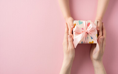 A beautifully wrapped pink gift box being exchanged between two people, symbolizing care and appreciation