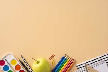 Colorful school supplies including pencils, a notebook, an apple, and more on a soft beige...