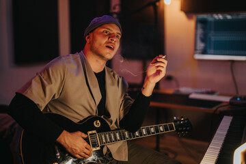 A musician performs on a guitar while sitting in a recording studio. The setting is cozy,...