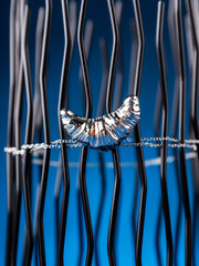 Close up of silver croissant brooch on blue background