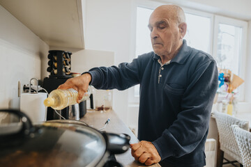 An elderly man is seen pouring oil while standing in a modern kitchen, emphasizing his independence...