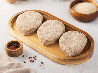 Cutlets cooked for frying with breadcrumbs on a wooden board.