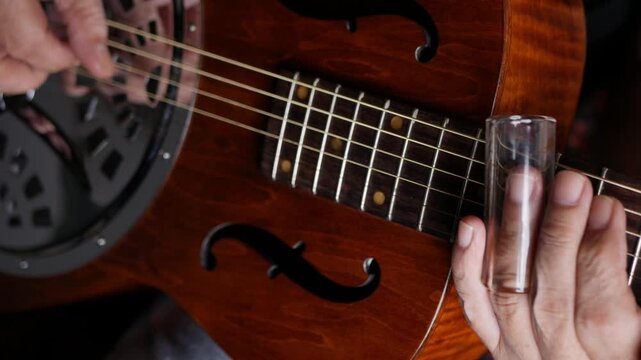 Male musician hand play Vintage Resonator acoustic dobro blues slide guitar.