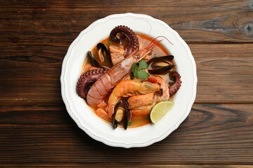 Delicious seafood soup in bowl on wooden table, top view