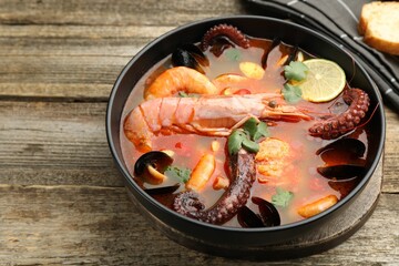 Delicious seafood soup in bowl on wooden table, closeup