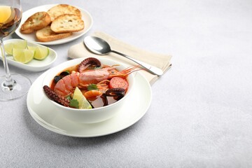 Tasty seafood soup served on light grey table, space for text