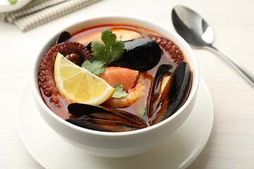 Delicious seafood soup served on light wooden table, closeup