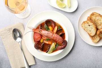 Tasty seafood soup served on light grey table, flat lay