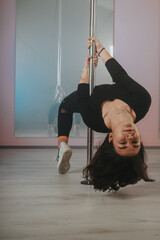 A talented individual executes a pole dancing pose, demonstrating strength, balance, and...