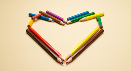 Colorful pencils form a heart a symbol of love and creativity on a beige background Simple yet