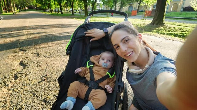 POV of a young mother making a video call or selfie after a run in the park at sunset with her baby in the runner stroller. Concept of: sport, family, fitness and connection